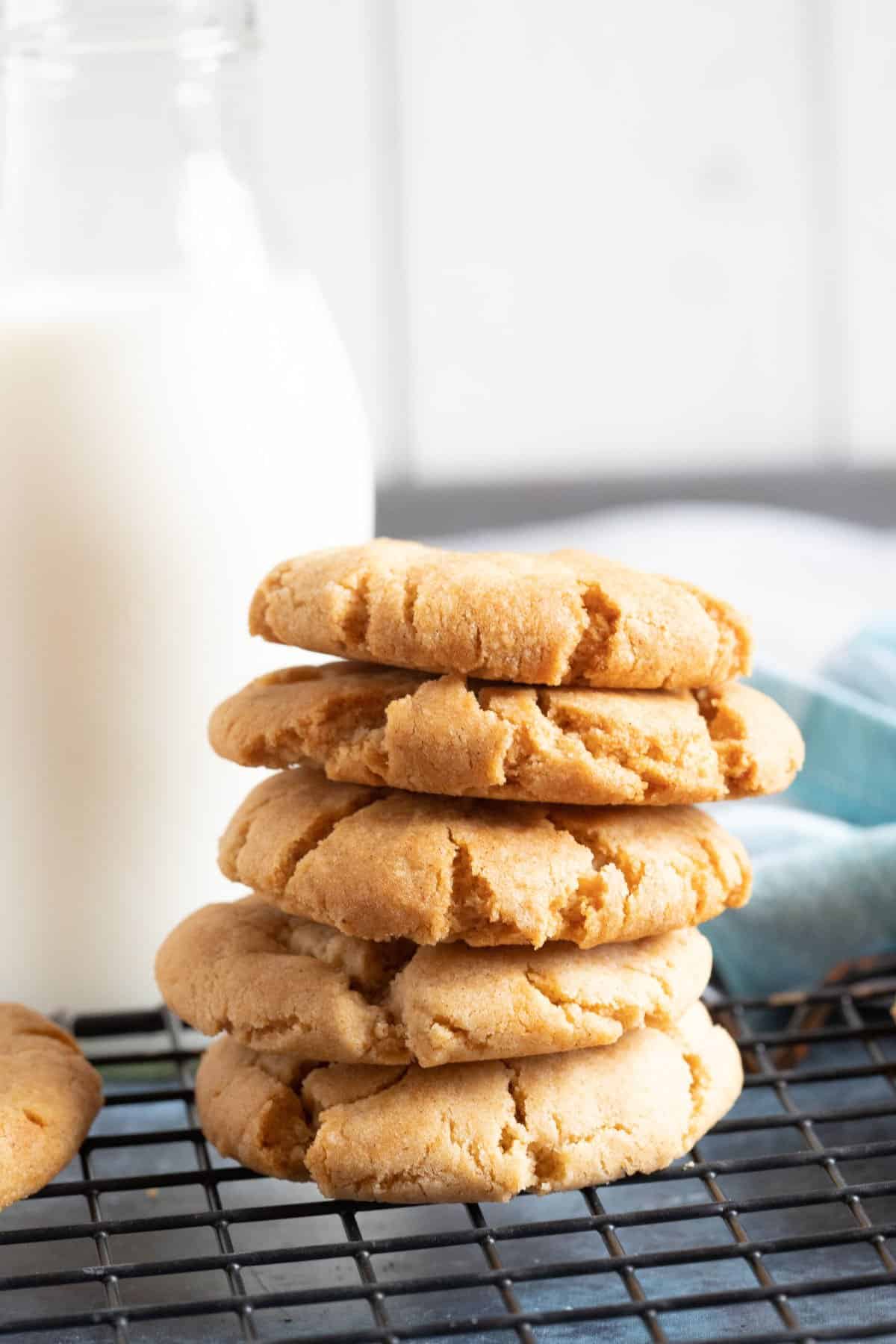 A stack of ginger cookies with a glass of milk.
