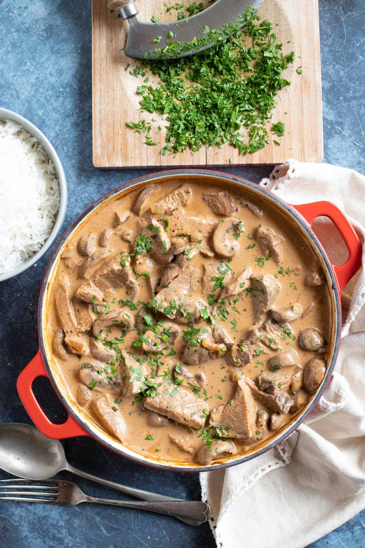 Leftover roast beef stroganoff in a pan with a bowl of rice.