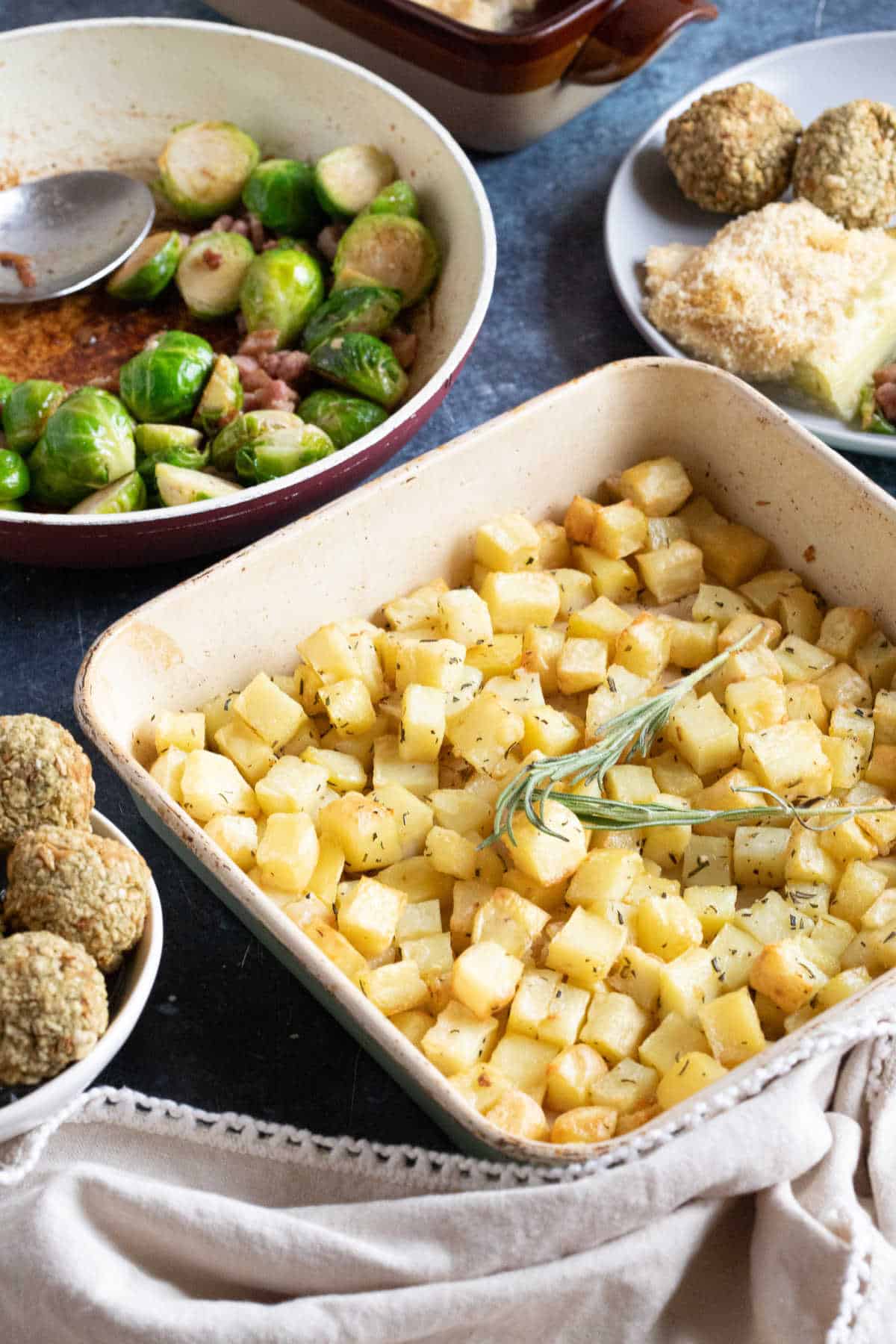 Parmentier potatoes with garlic and herbs in a roasting tin.