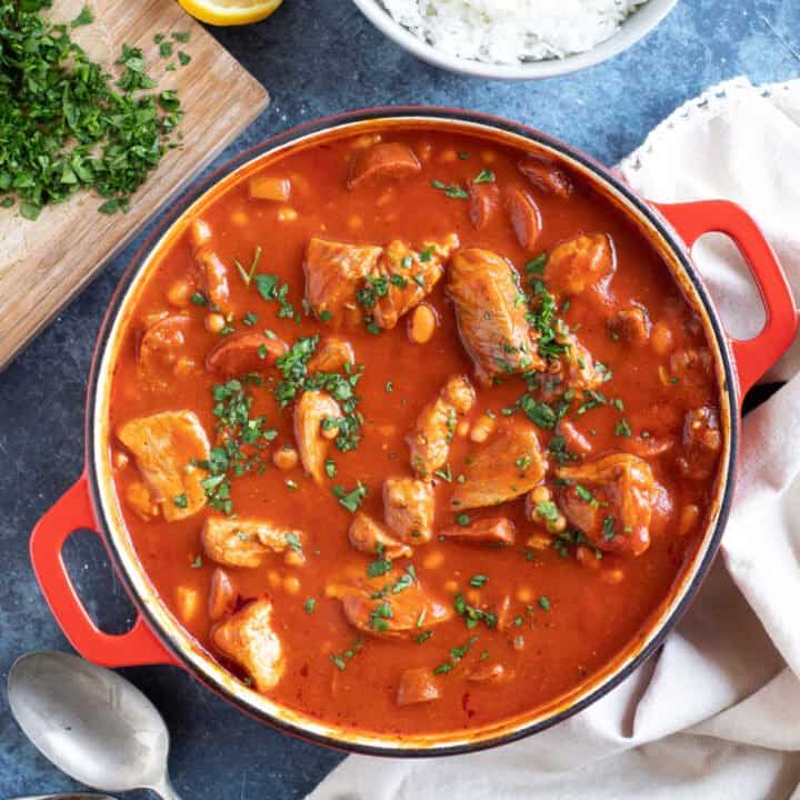 Pork and chorizo stew in a red casserole.