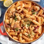 Creamy chorizo and prawn pasta in a red pan.