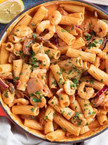 Creamy chorizo and prawn pasta in a red pan.