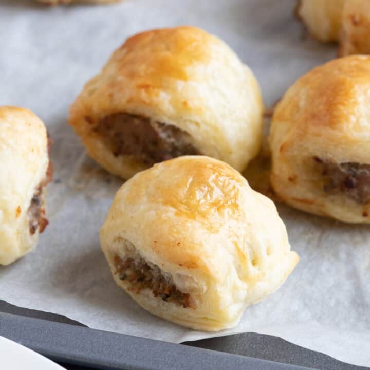 Mini sausage rolls on a baking sheet.