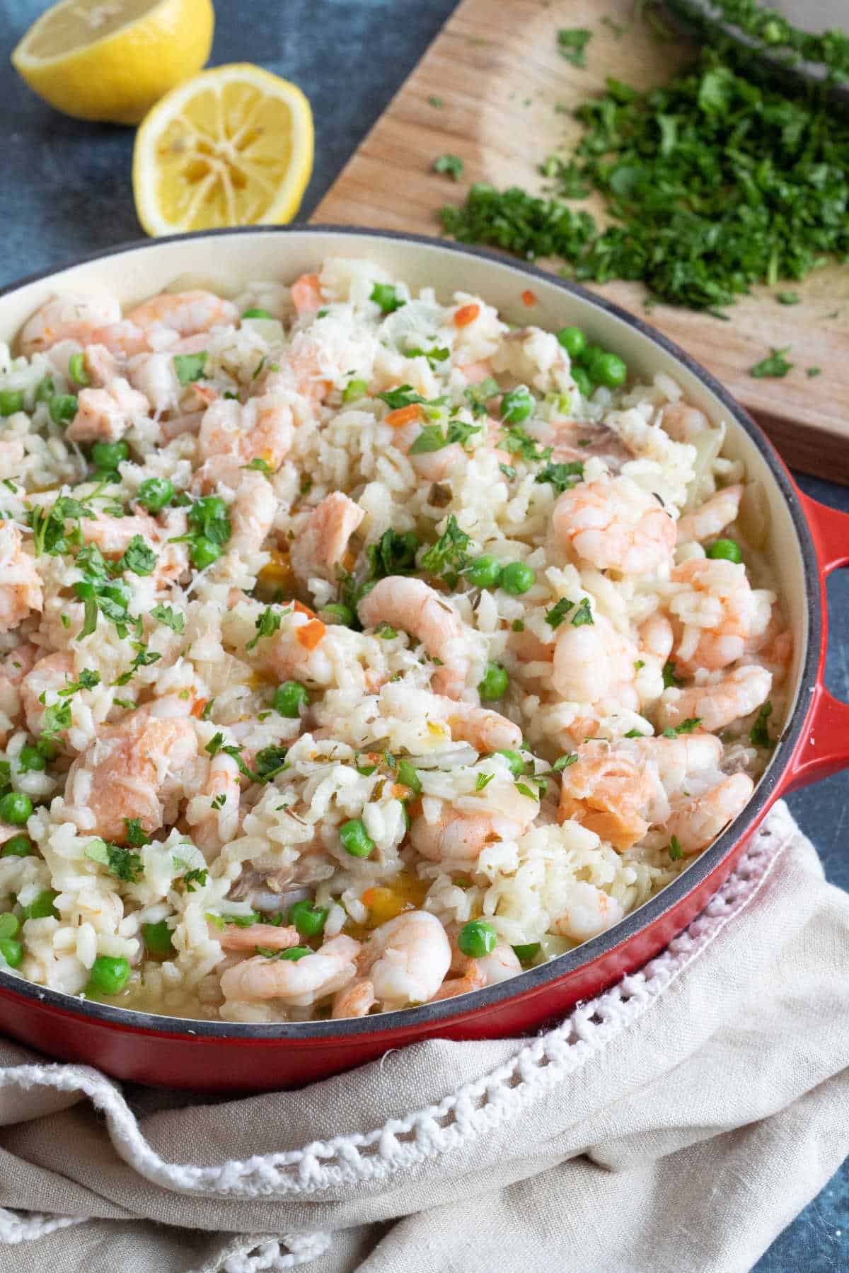 Smoked salmon and prawn risotto with lemon wedges.