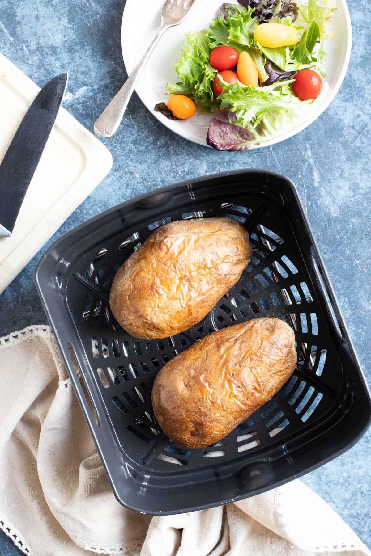 Jacket potatoes in a ninja foodi air fryer basket.