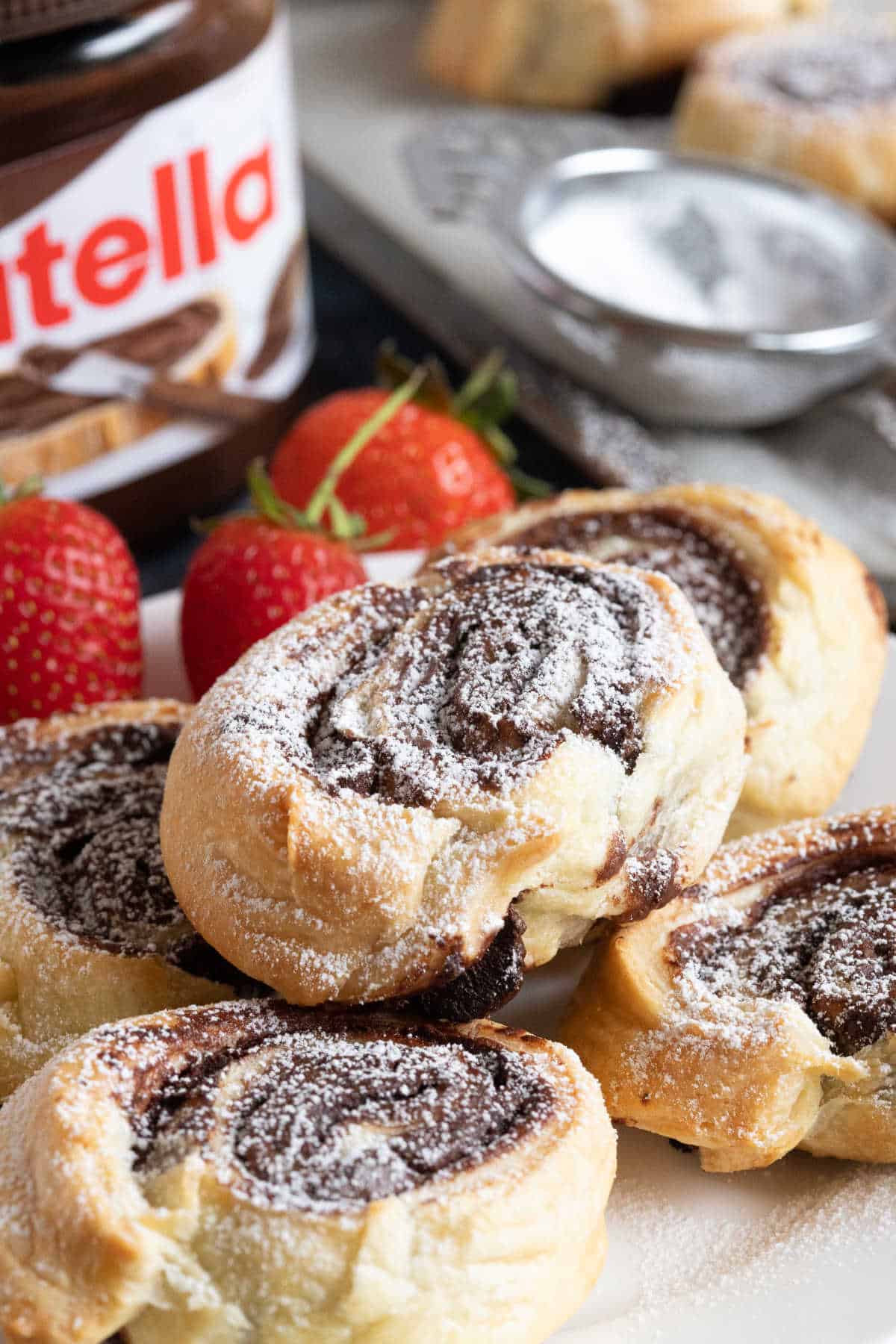 Nutella swirls piled onto a plate with a jar of Nutella in the background.