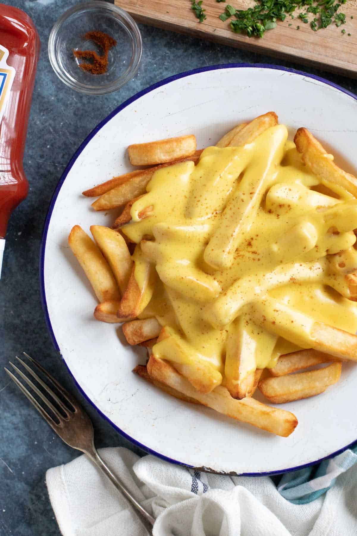 A plate of cheesy chips with ketchup.