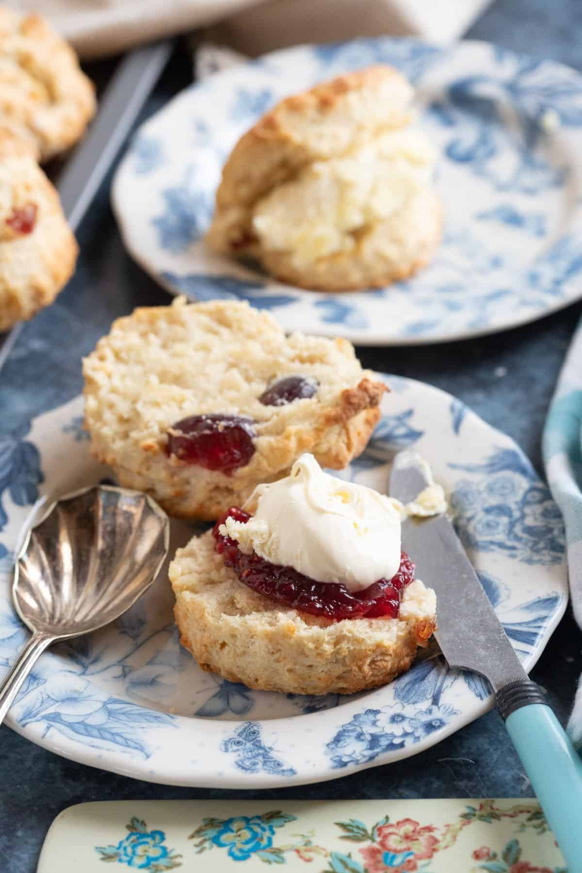 Cherry and almond scone on a tea plate served with jam and clotted cream.