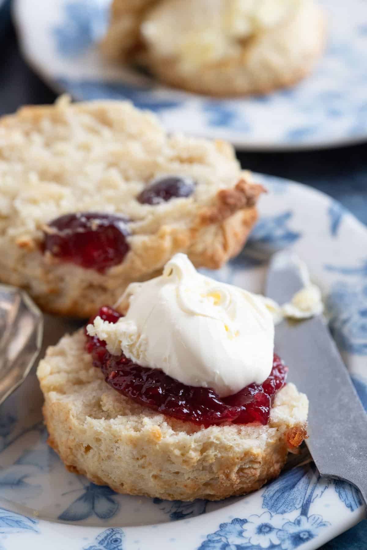 Close-up of a cherry and almond scone served with jam and clotted cream.