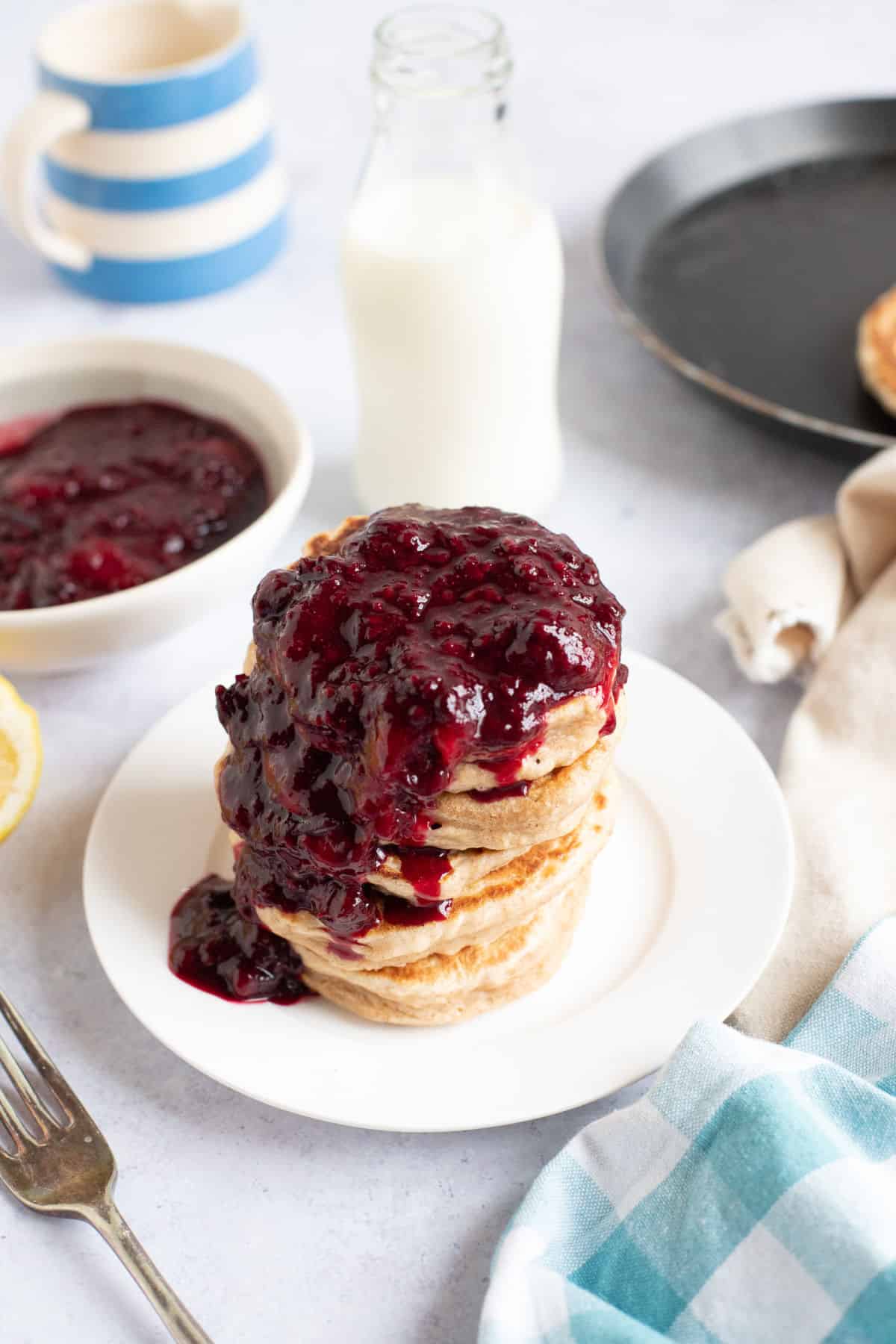 A stack of pancakes with mixed fruit compote.