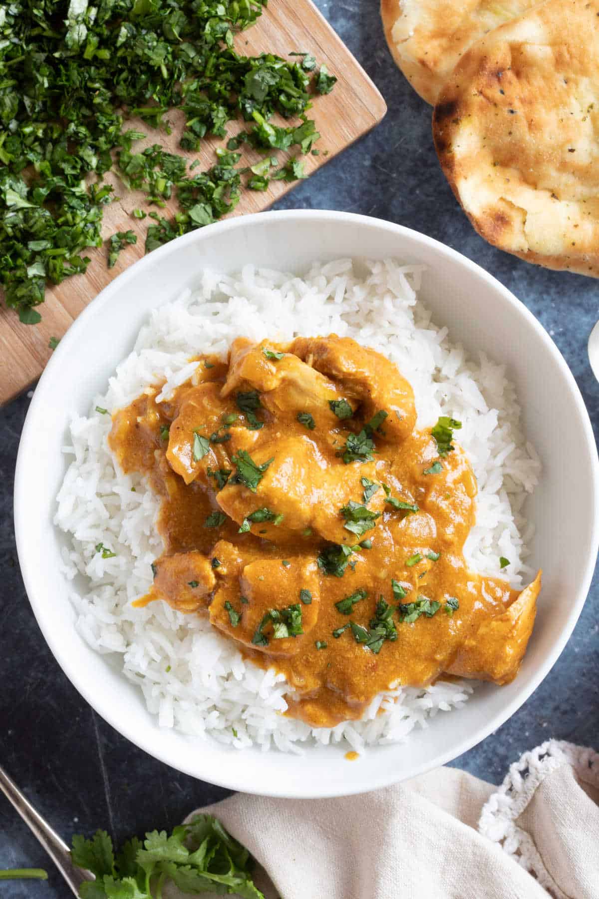 Slow cooker chicken curry with coconut milk served in a white bowl with naan bread.