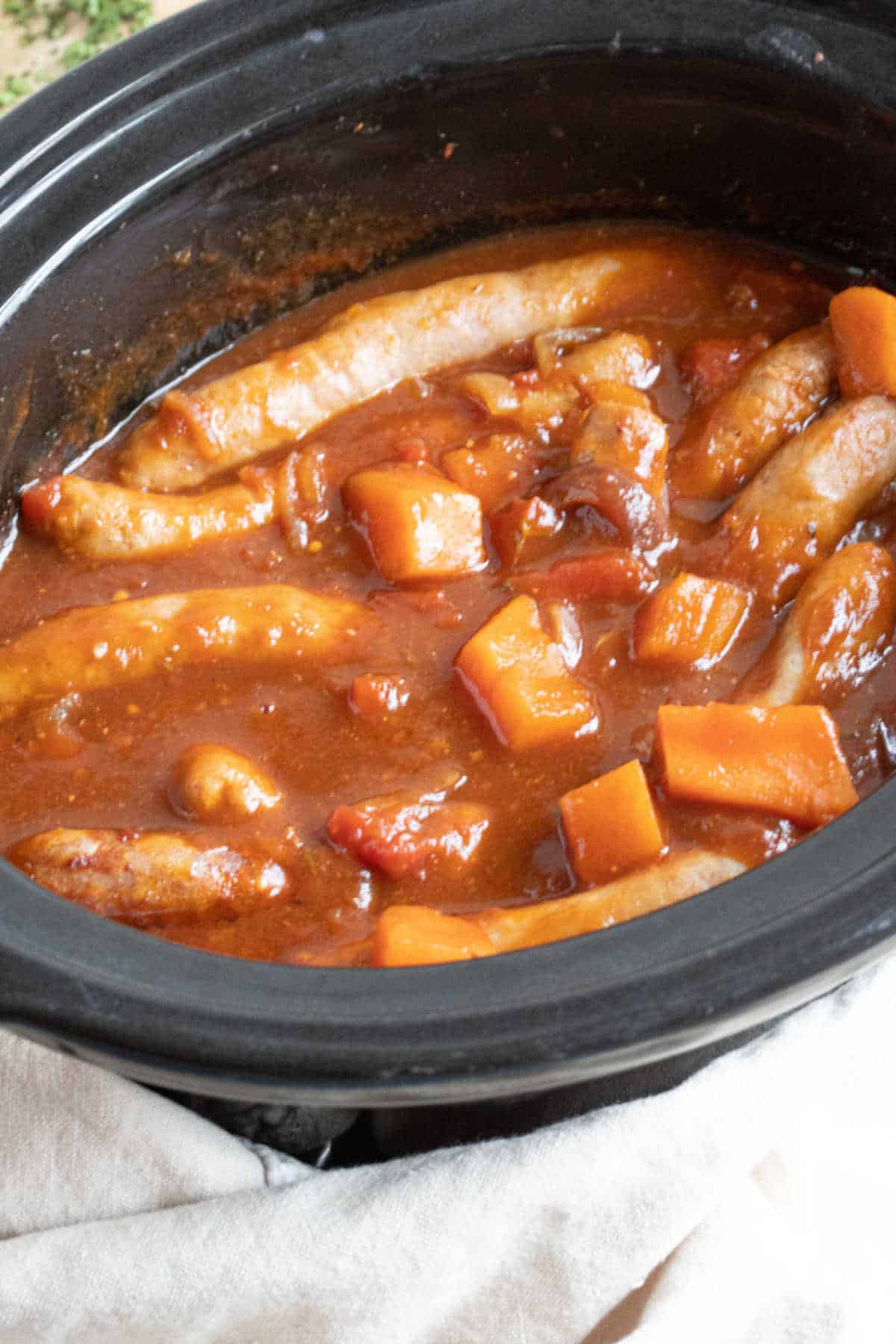 Slow cooker sausage casserole in a black crockpot.