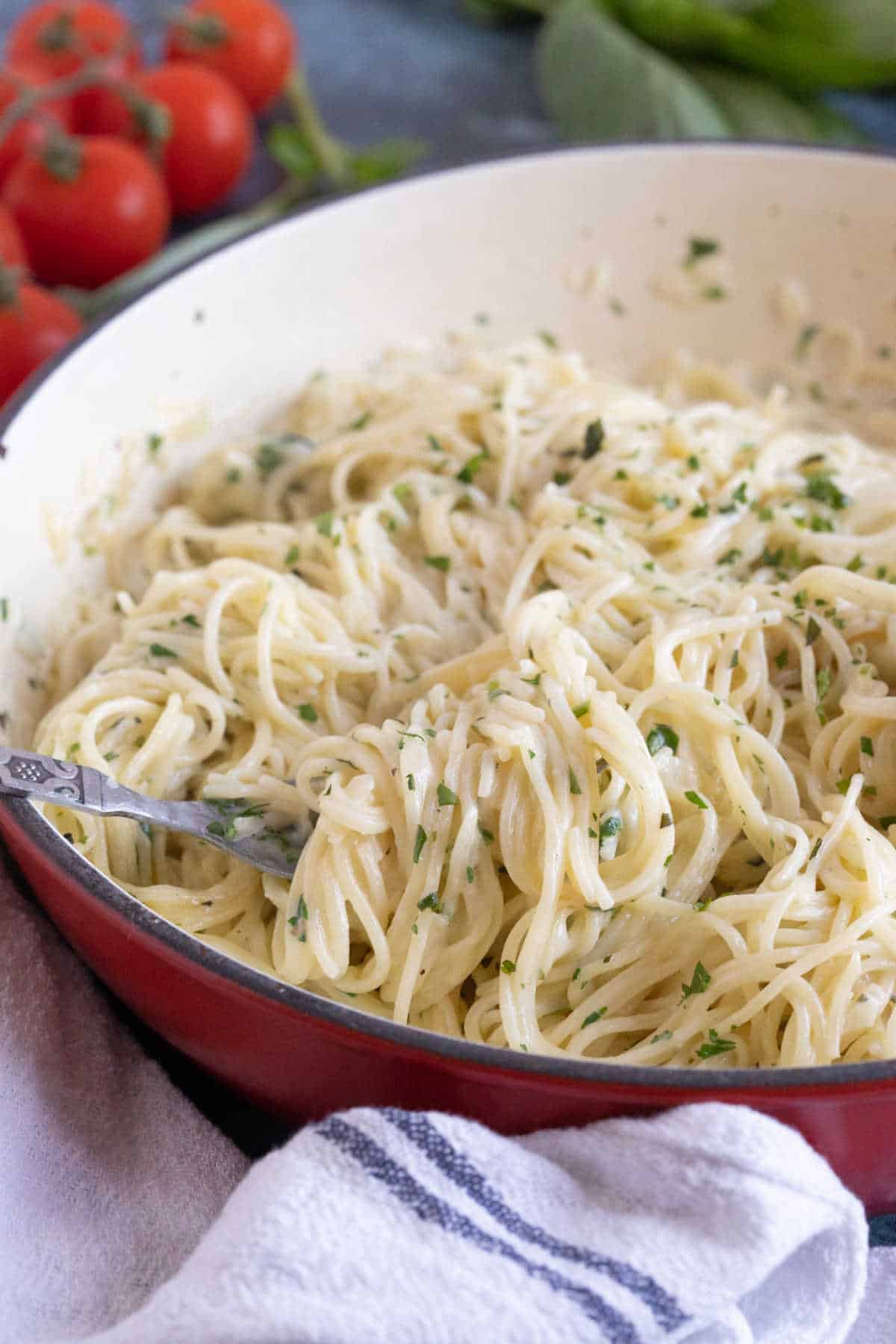 Cooked angel hair pasta in a red pan.