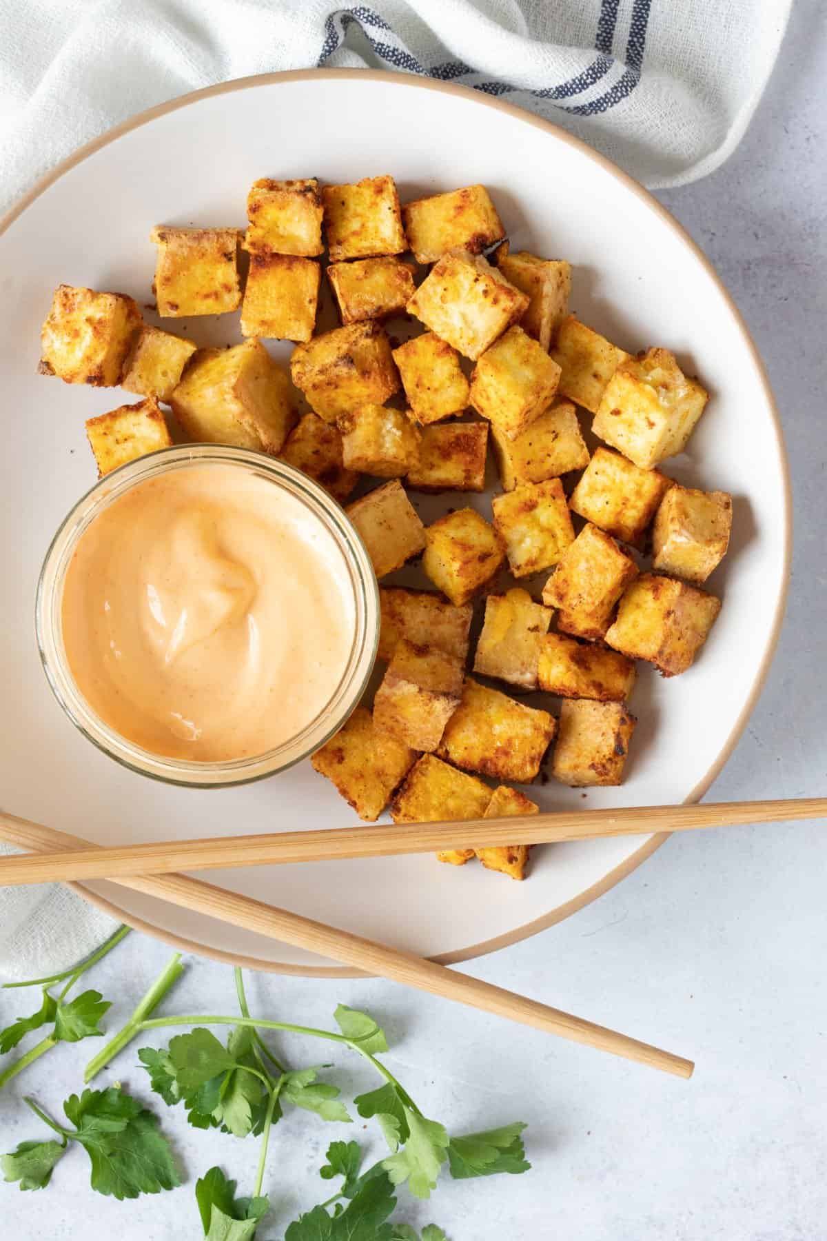 Air fried tofu on a plate with a dipping sauce.