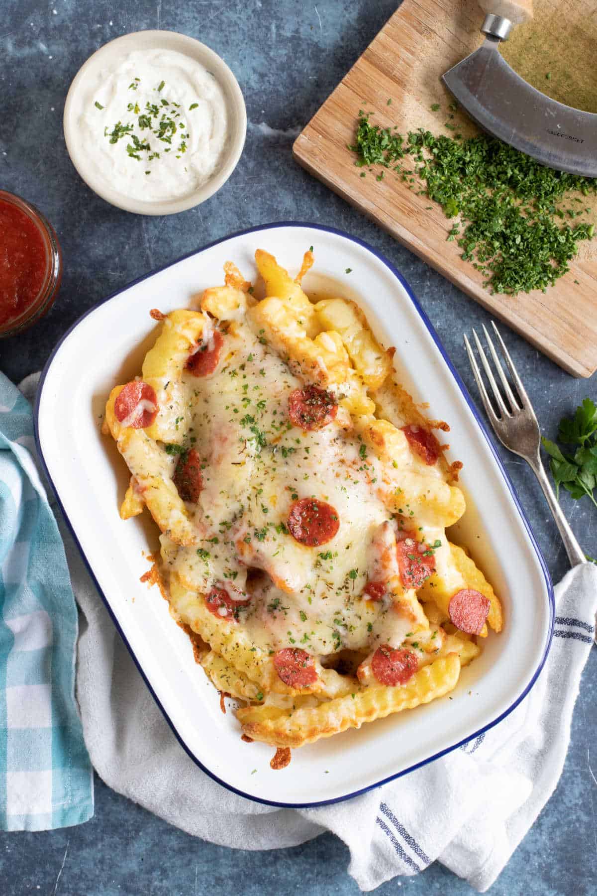 Loaded pizza fries in a white baking tin.
