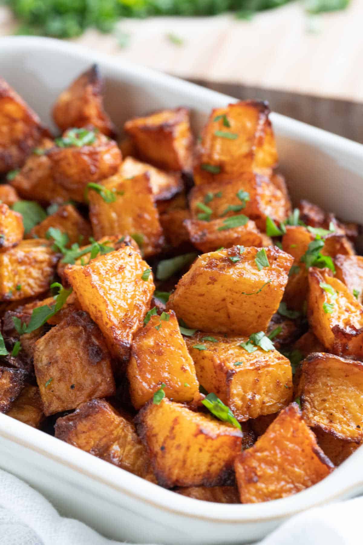 Roasted swede in a serving dish garnished with chopped parsley.