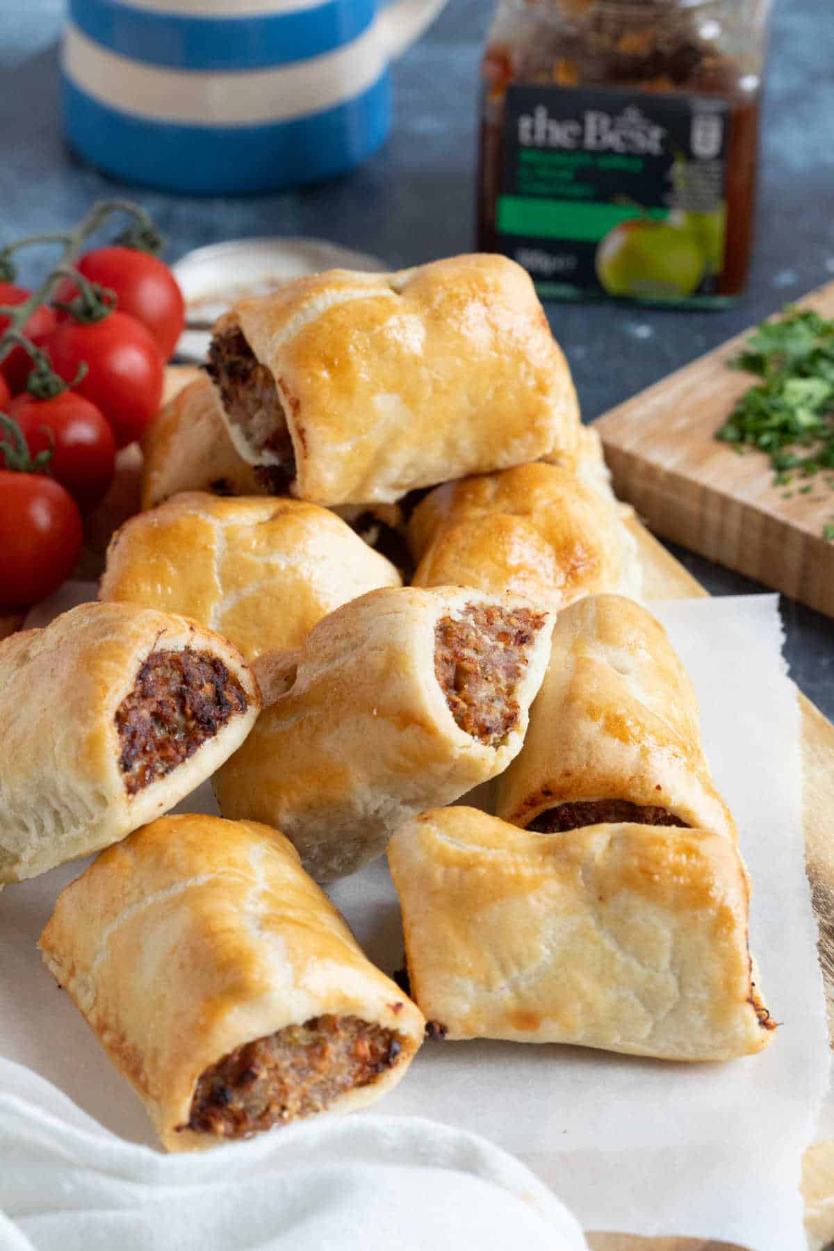 Shortcrust pastry sausage rolls on a wooden board.