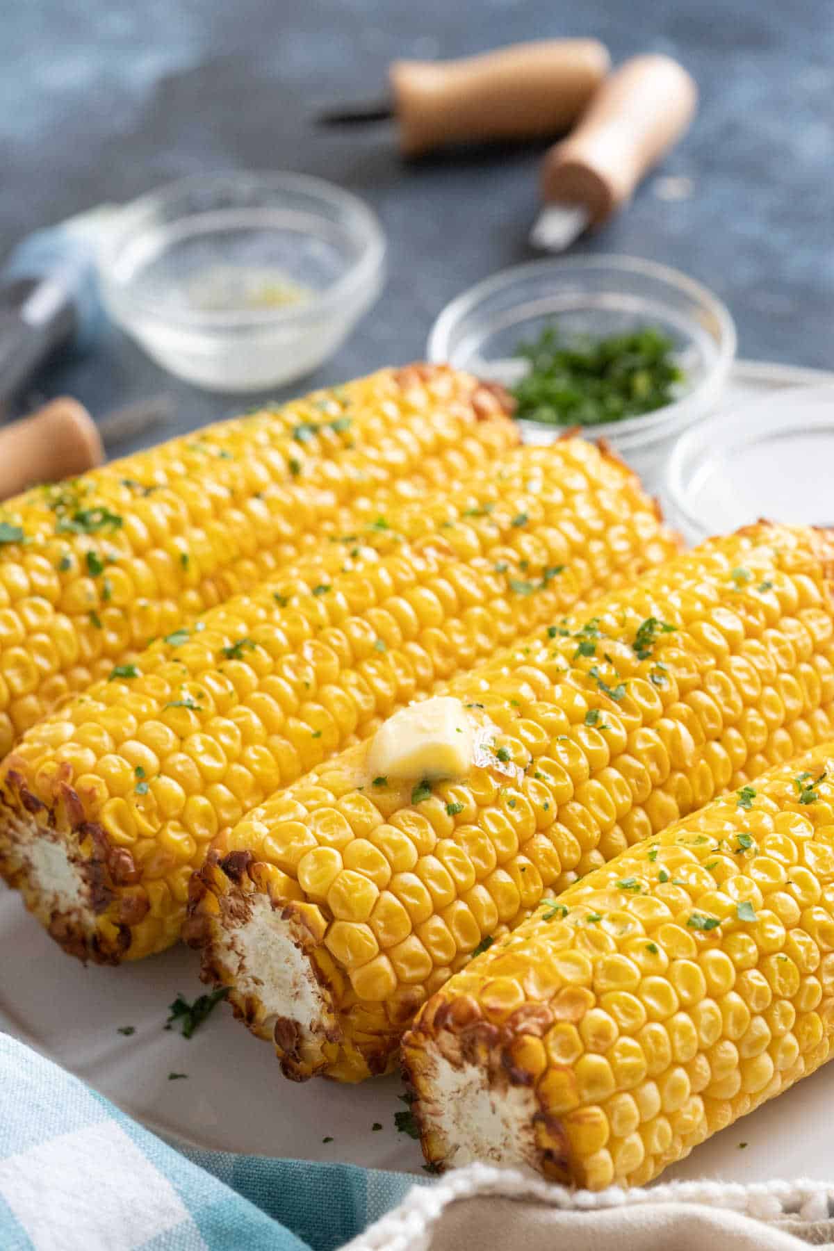 Air fryer corn on the cob with melted butter and parsley.