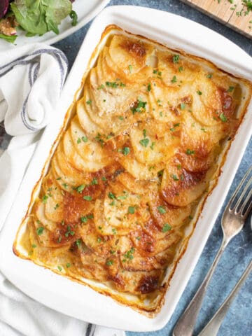 Boulangere potatoes in a white ovenproof dish.