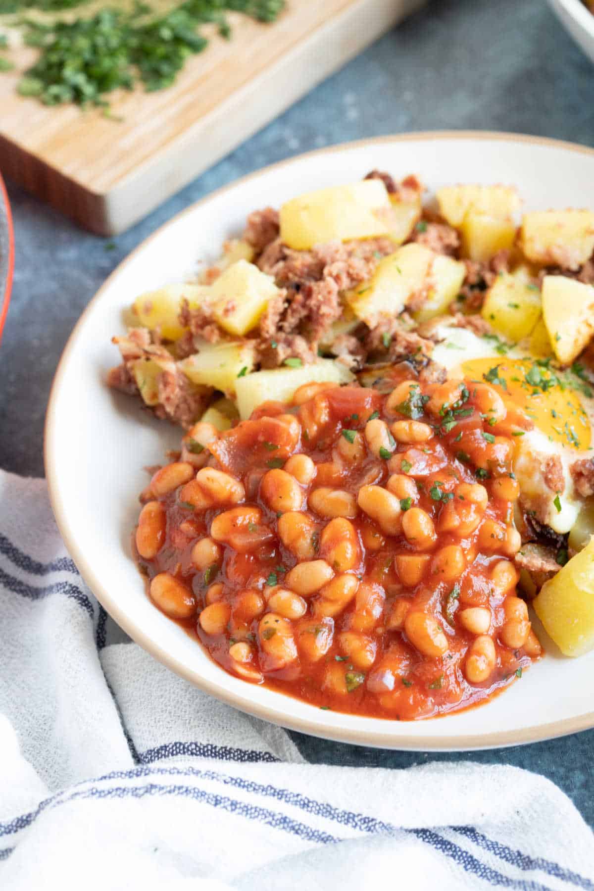 A plate of baked beans, fried egg, and potatoes.