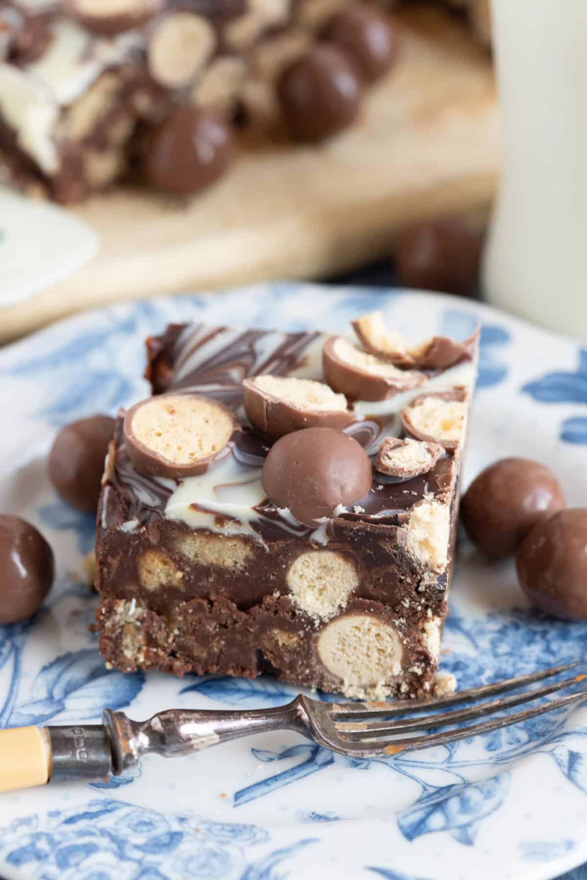 A slice of Malteser tiffin on a blue and white plate.