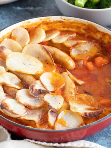 Sausage hotpot with thinly sliced potatoes.
