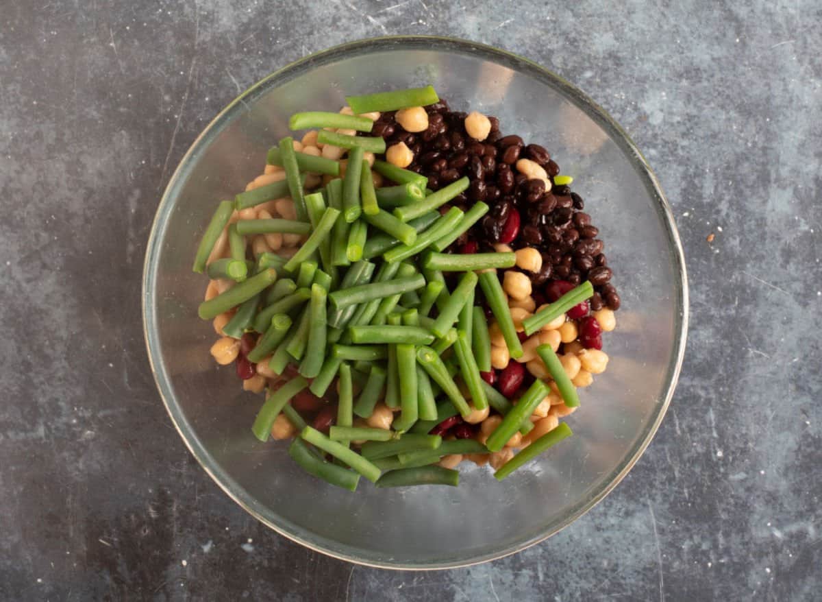 Green beans added to the canned beans in a bowl.