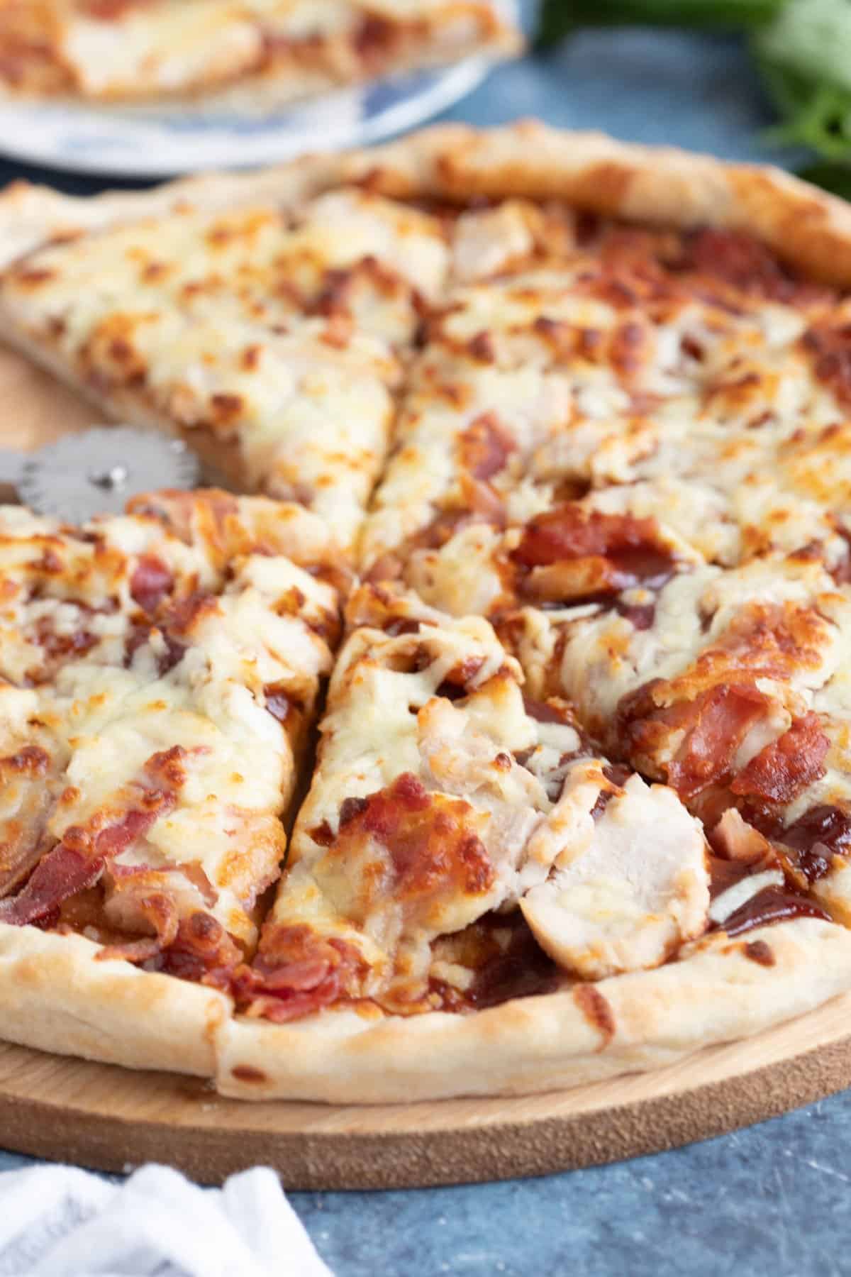 BBQ chicken and bacon pizza cut into slices.