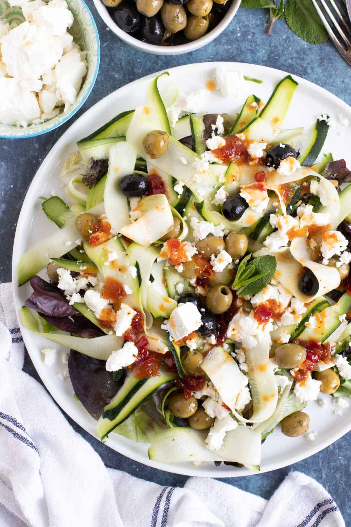 Courgette, feta and olive salad in a white serving plate.