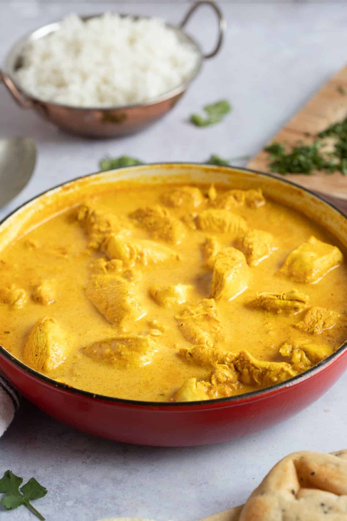 Creamy chicken korma in a red pan.