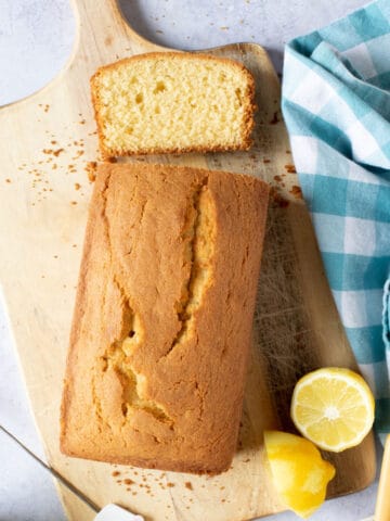 Madeira loaf cake on a wooden board with a slice cut.