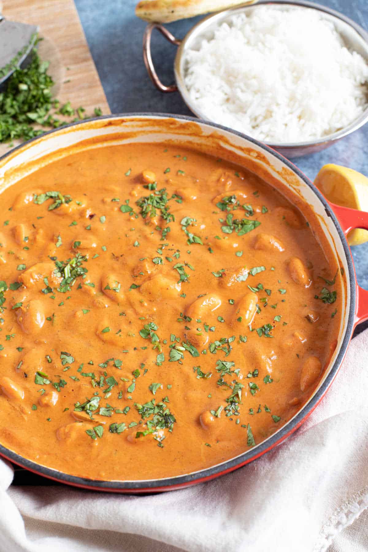 Prawn curry in a pan with rice and chopped coriander.