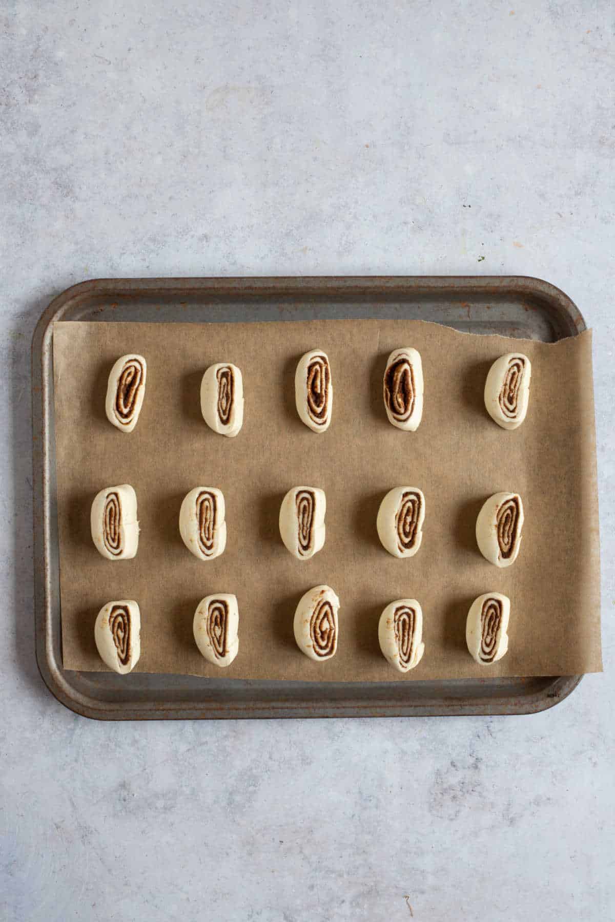 Puff pastry cinnamon swirls on a baking sheet.