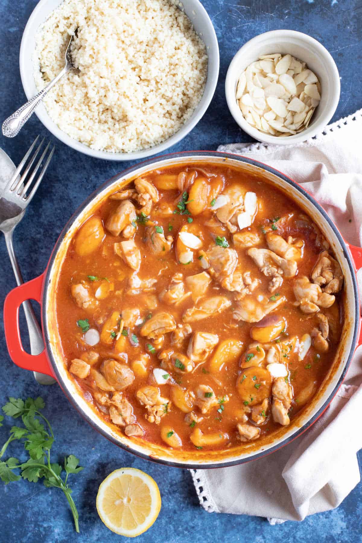 Easy Moroccan chicken tagine with apricots and almonds in a red pan.