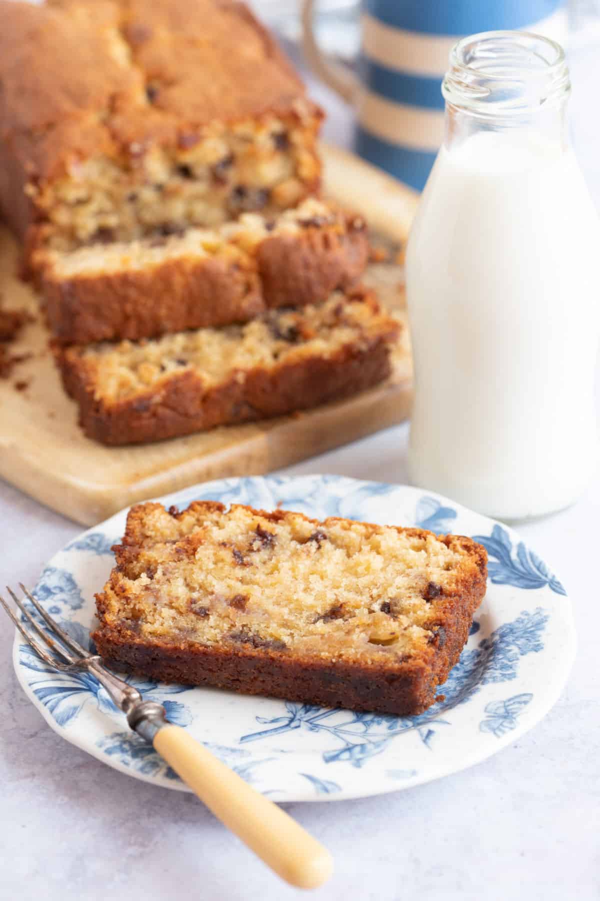 A slice of moist chocolate chip banana bread with a glass of milk.