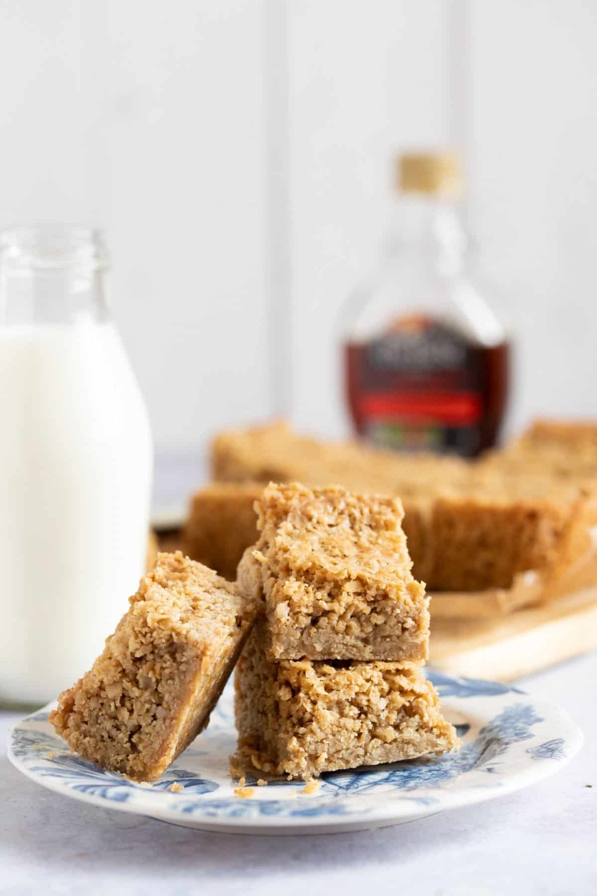 A plate of maple syrup flapjacks with a glass of milk.