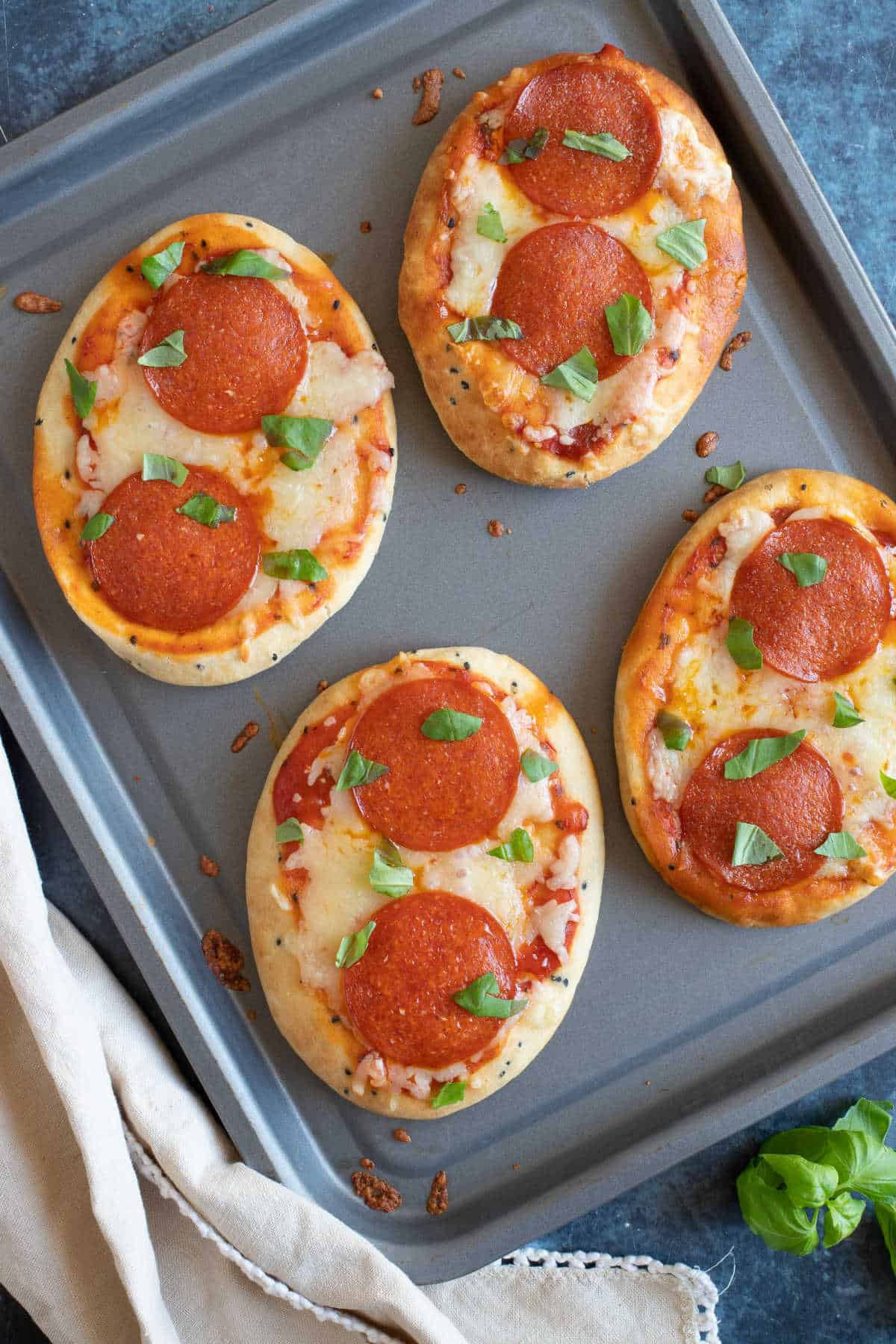 A baking tray with 4 naan bread pizzas.