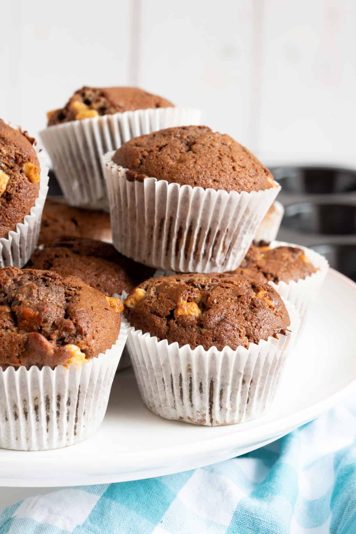 A stack of chocolate banana muffins on a white cake stand.