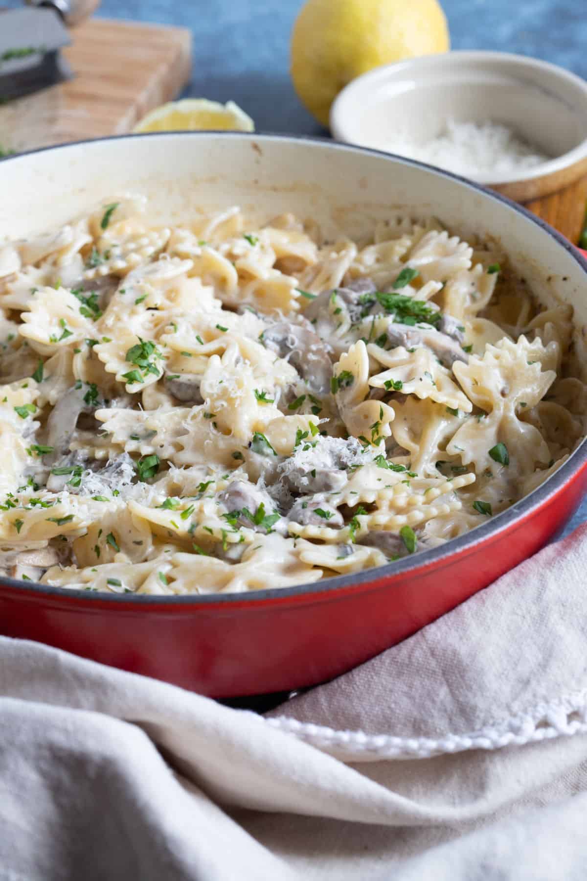 Garlic mushroom farfalle in a red pan.