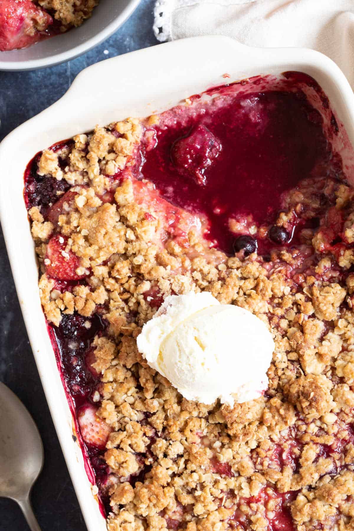 Frozen mixed berry crumble with a scoop of vanilla ice cream.