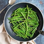 Stir fried garlic green beans in a black wok.