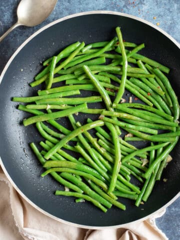 Stir fried garlic green beans in a black wok.
