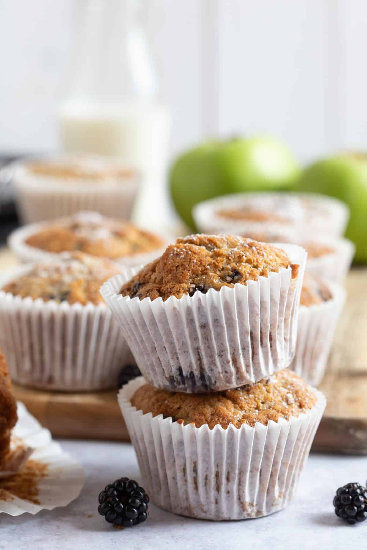 Two apple and blackberry muffins with a glass of milk.
