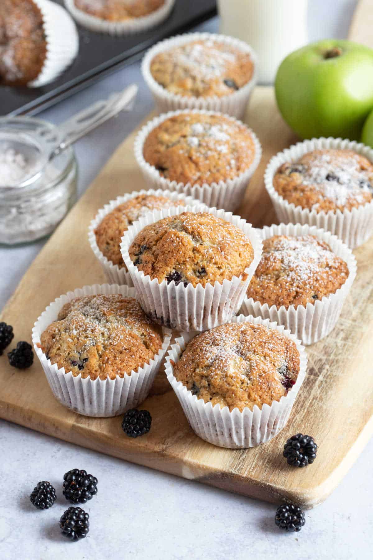 Apple and blackberry muffins on a wooden board.