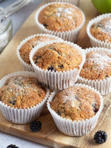 Apple and blackberry muffins on a wooden board.