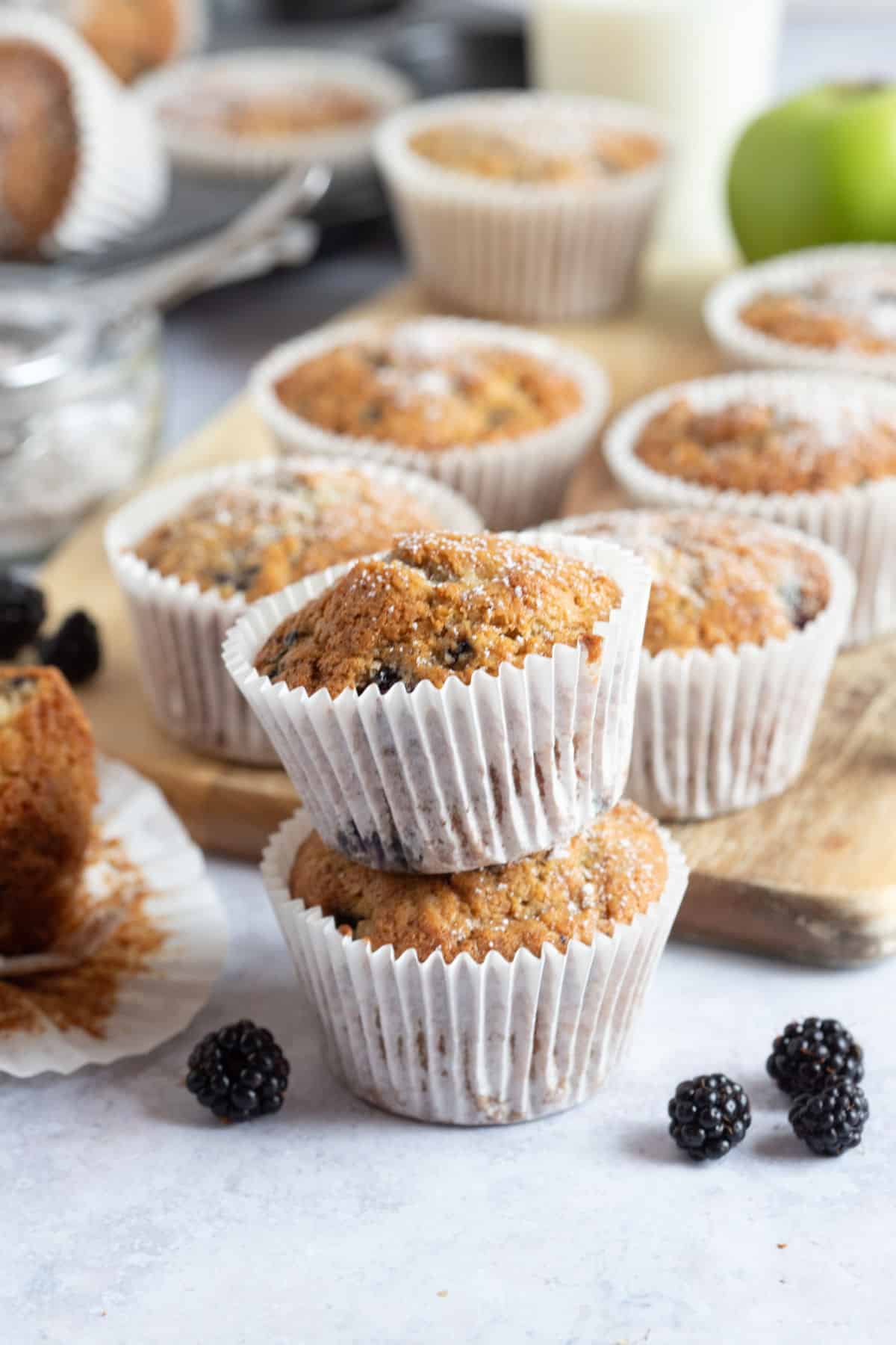 Two apple and blackberry muffins stacked on top of each other.