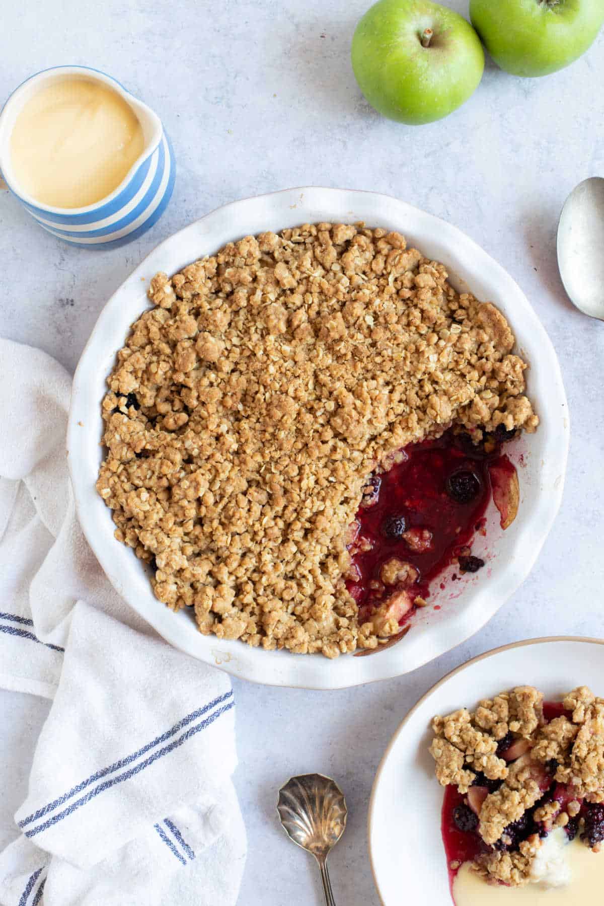 Blackberry and Apple Crumble in a pie dish with custard.