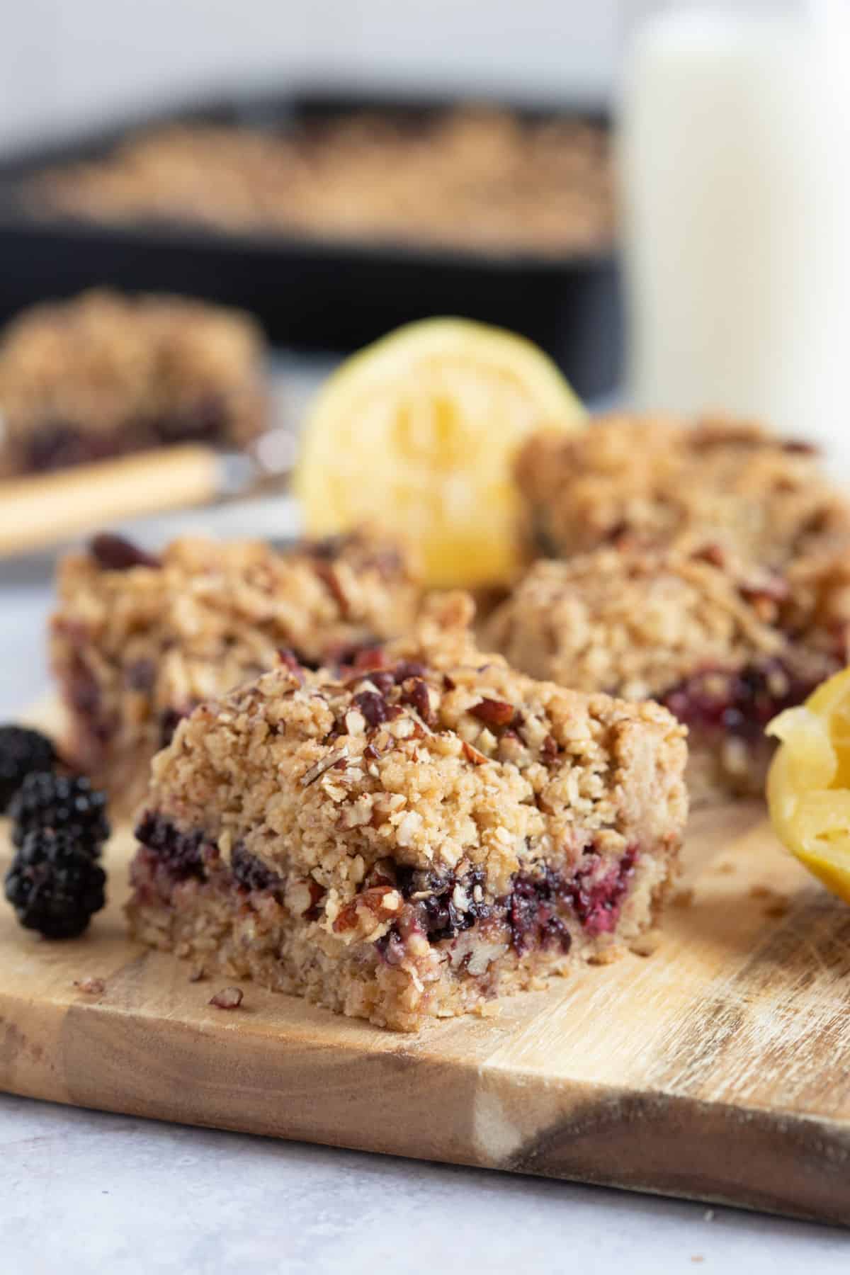A blackberry crumble bar on a wooden board.