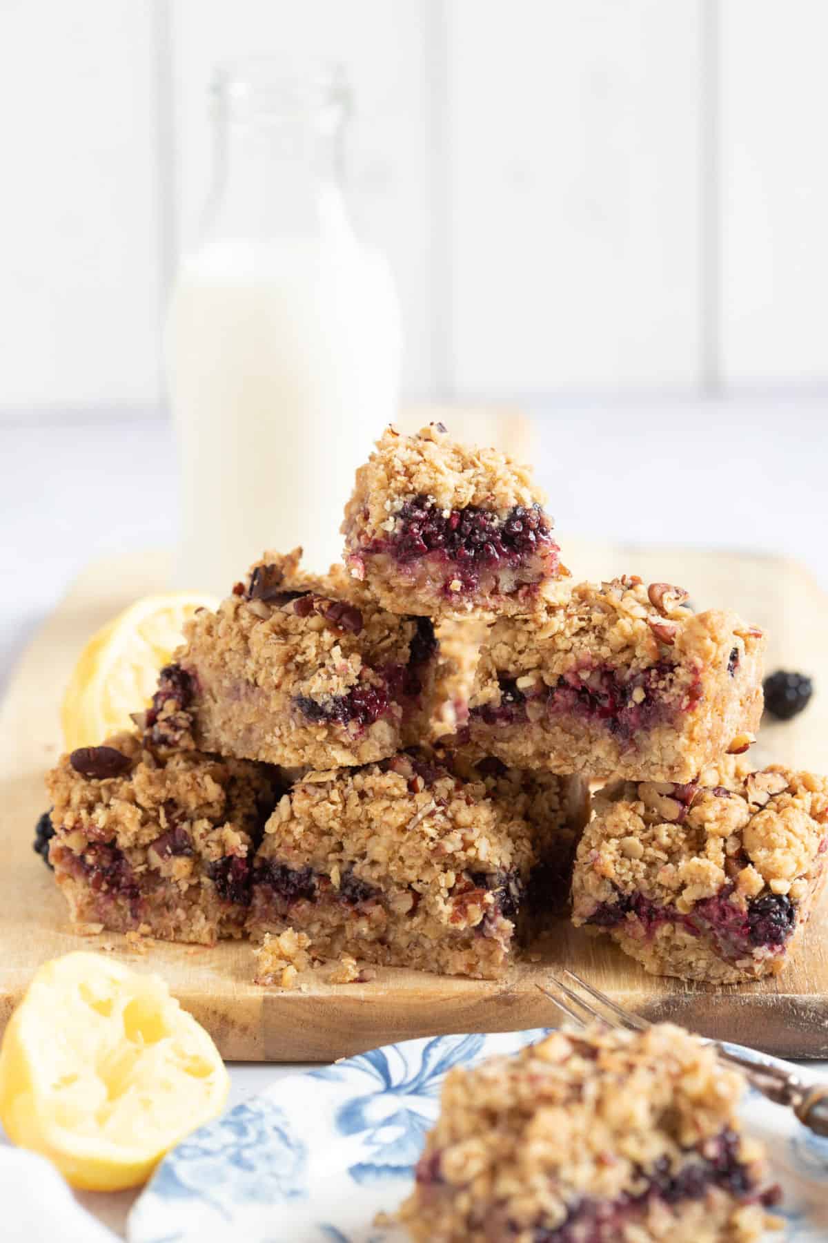 A stack of blackberry crumble bars on a wooden chopping board.