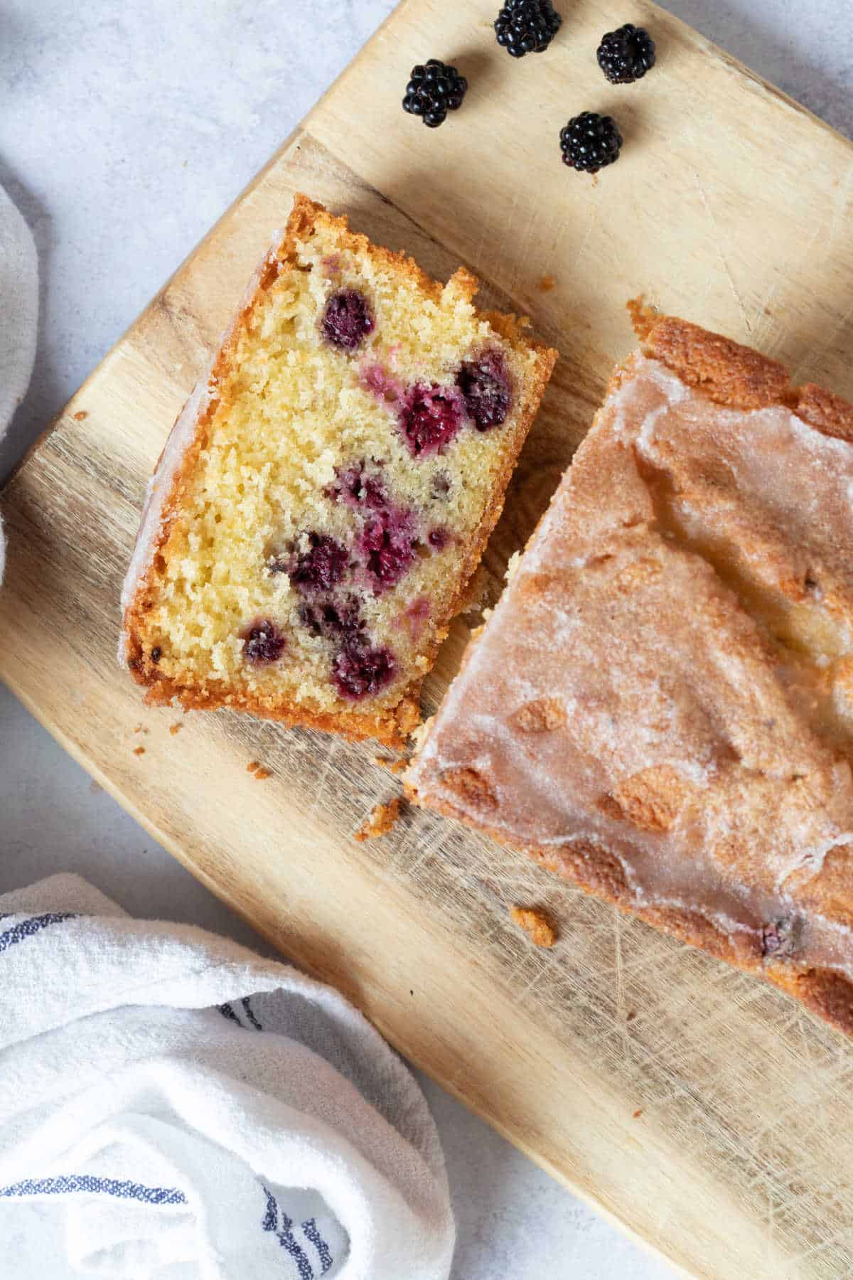 A slice of blackberry loaf cake on a wooden board.